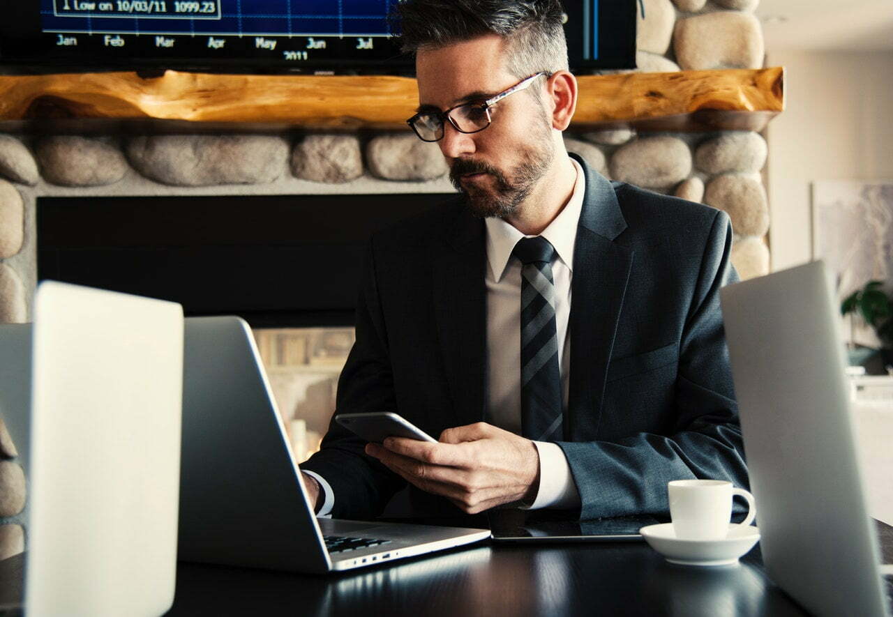 a man in a suit and tie sitting at a desk with a laptop