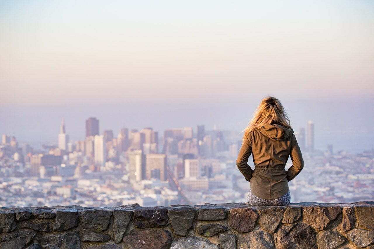 a person standing on a ledge overlooking a city