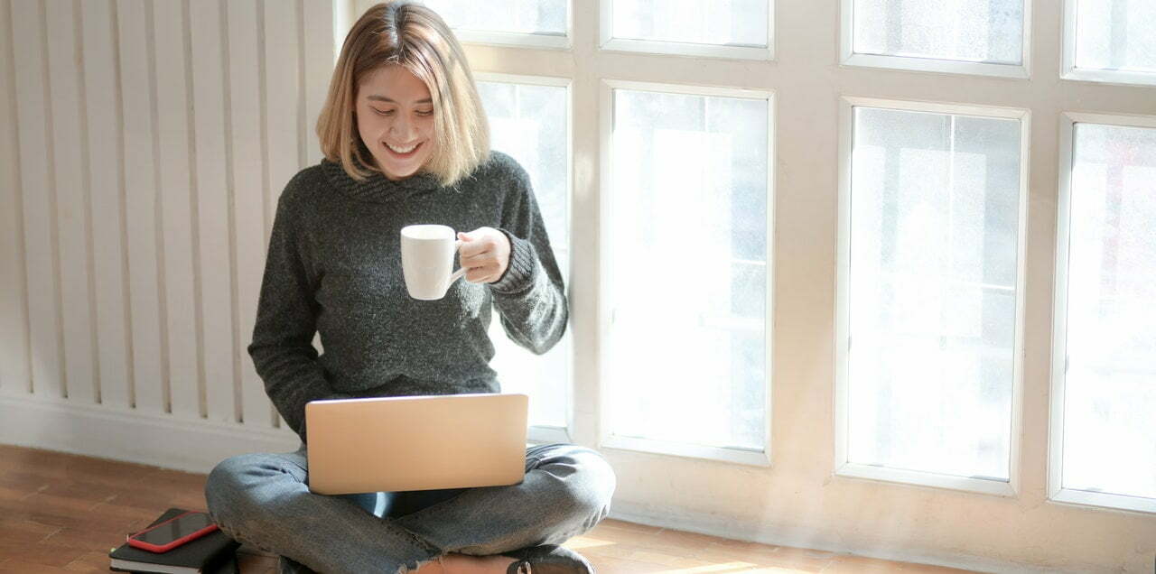 a woman holding a cup and a laptop