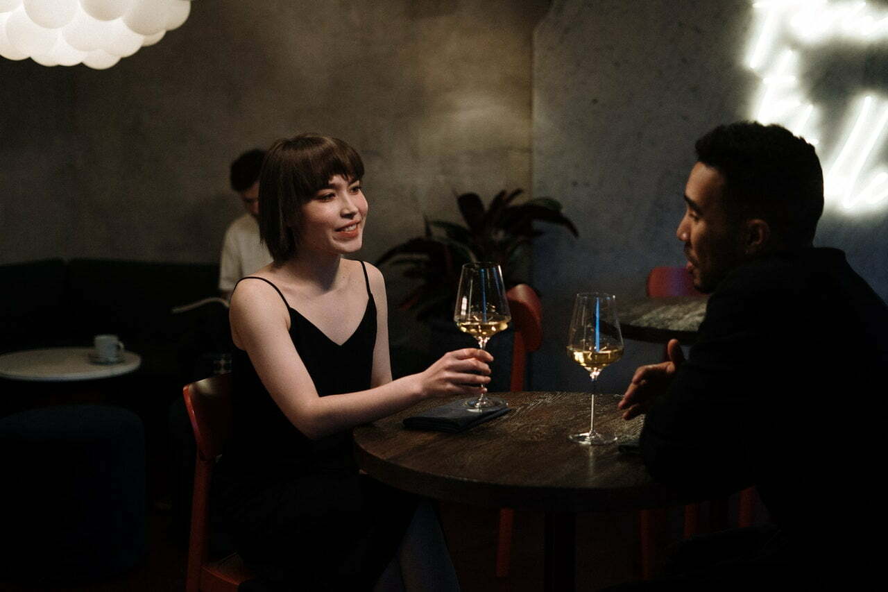 a man and a woman sitting at a table with wine glasses