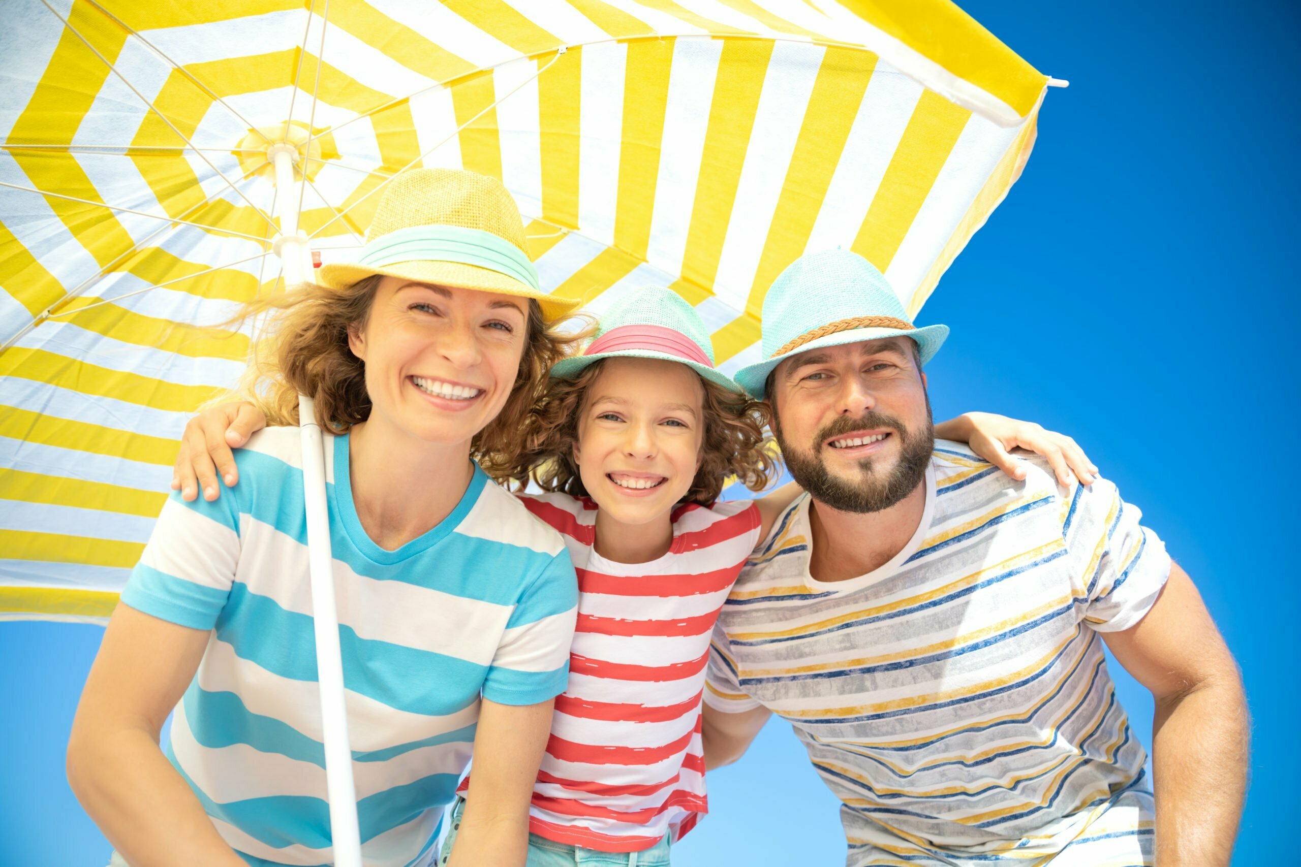 a family posing under a yellow umbrella