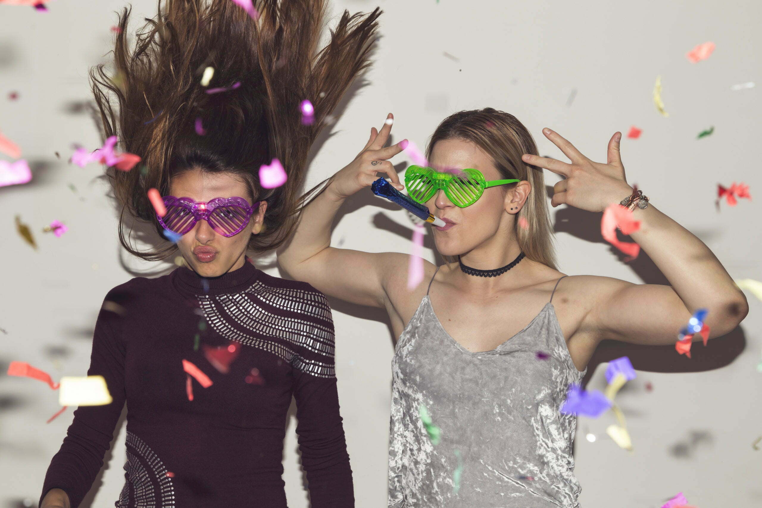 Two girl friends having fun, dancing and making crazy faces while taking photos at a party