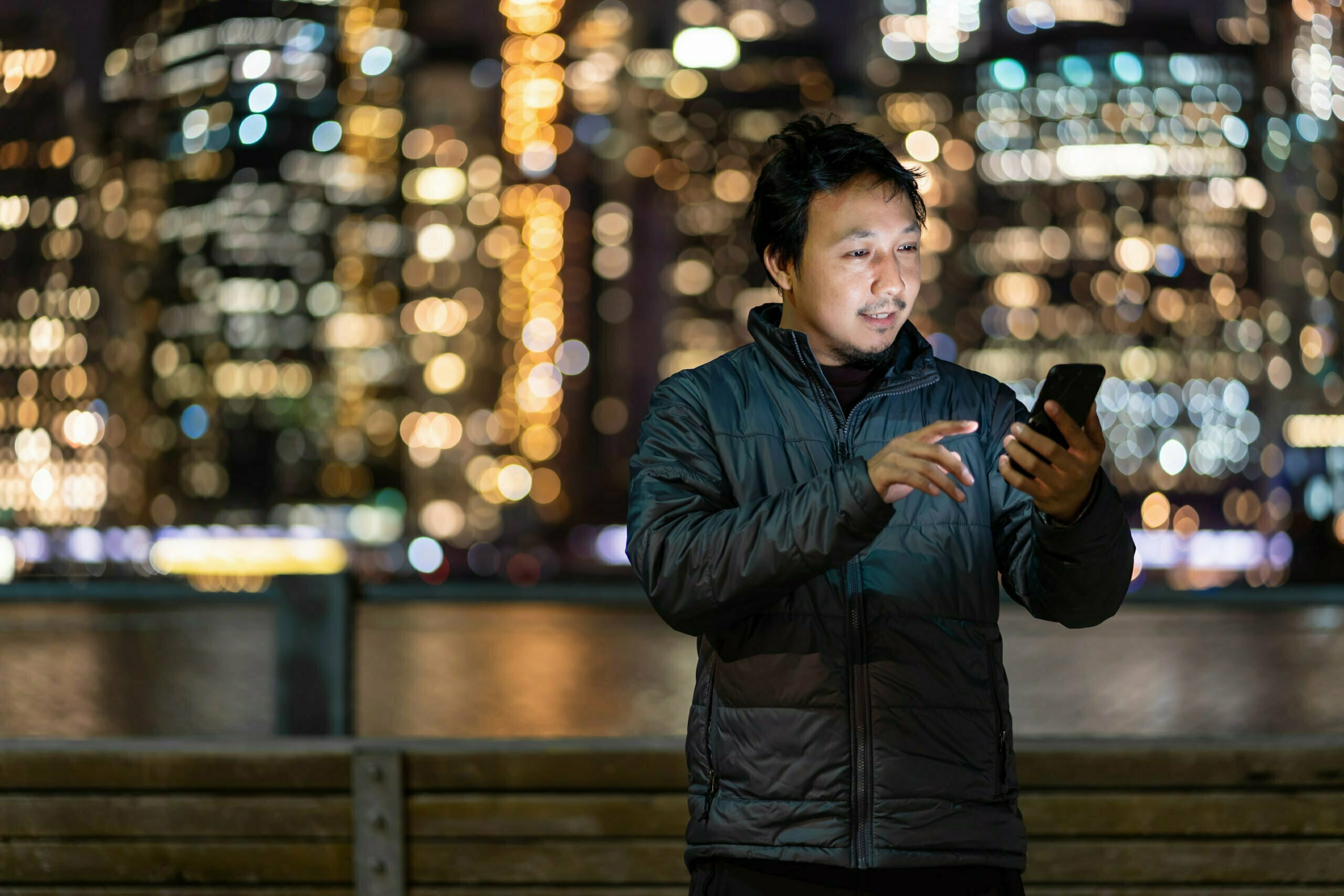 Asian man wearing overcoat suit using smart mobile phone with smile action