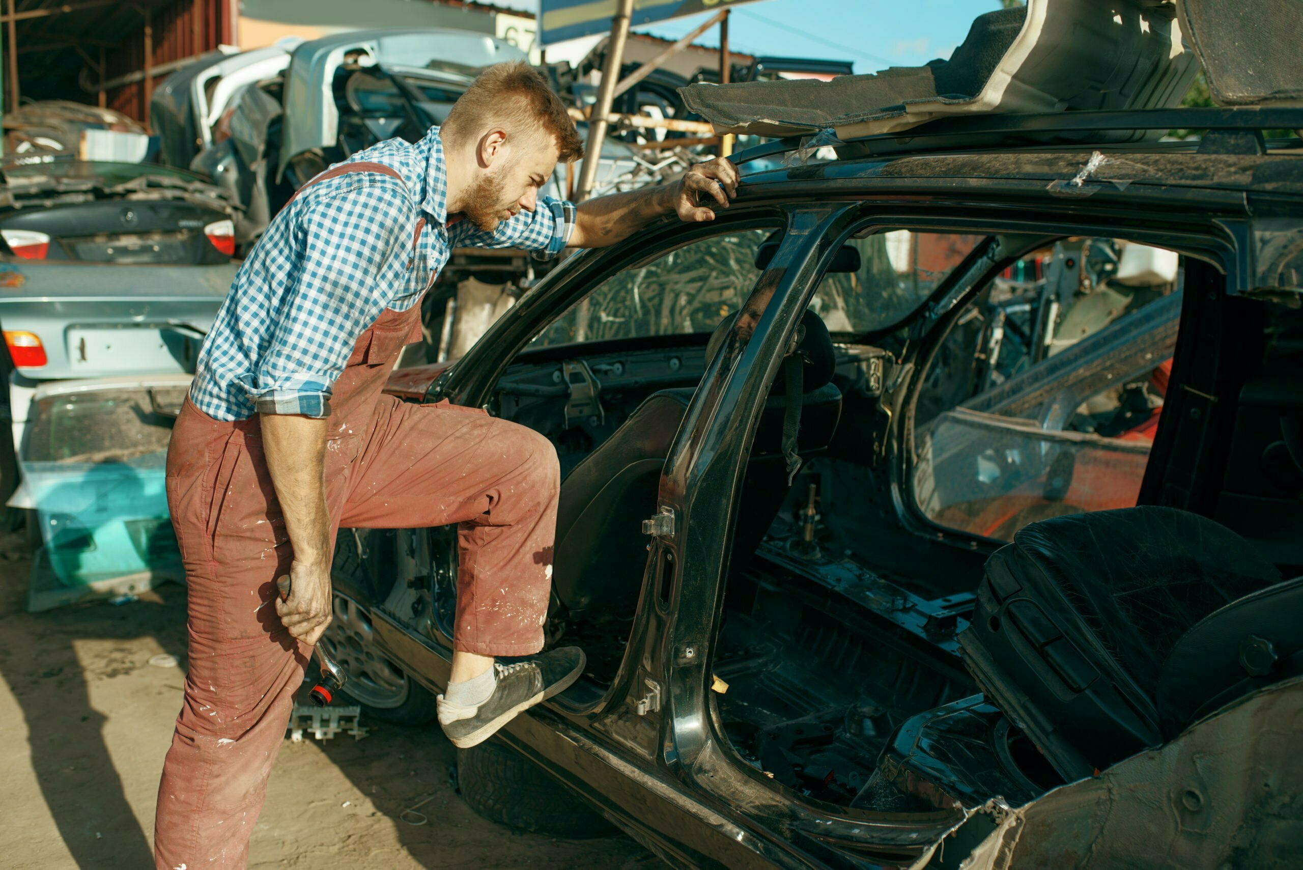 Male mechanic disassembles the car on junkyard