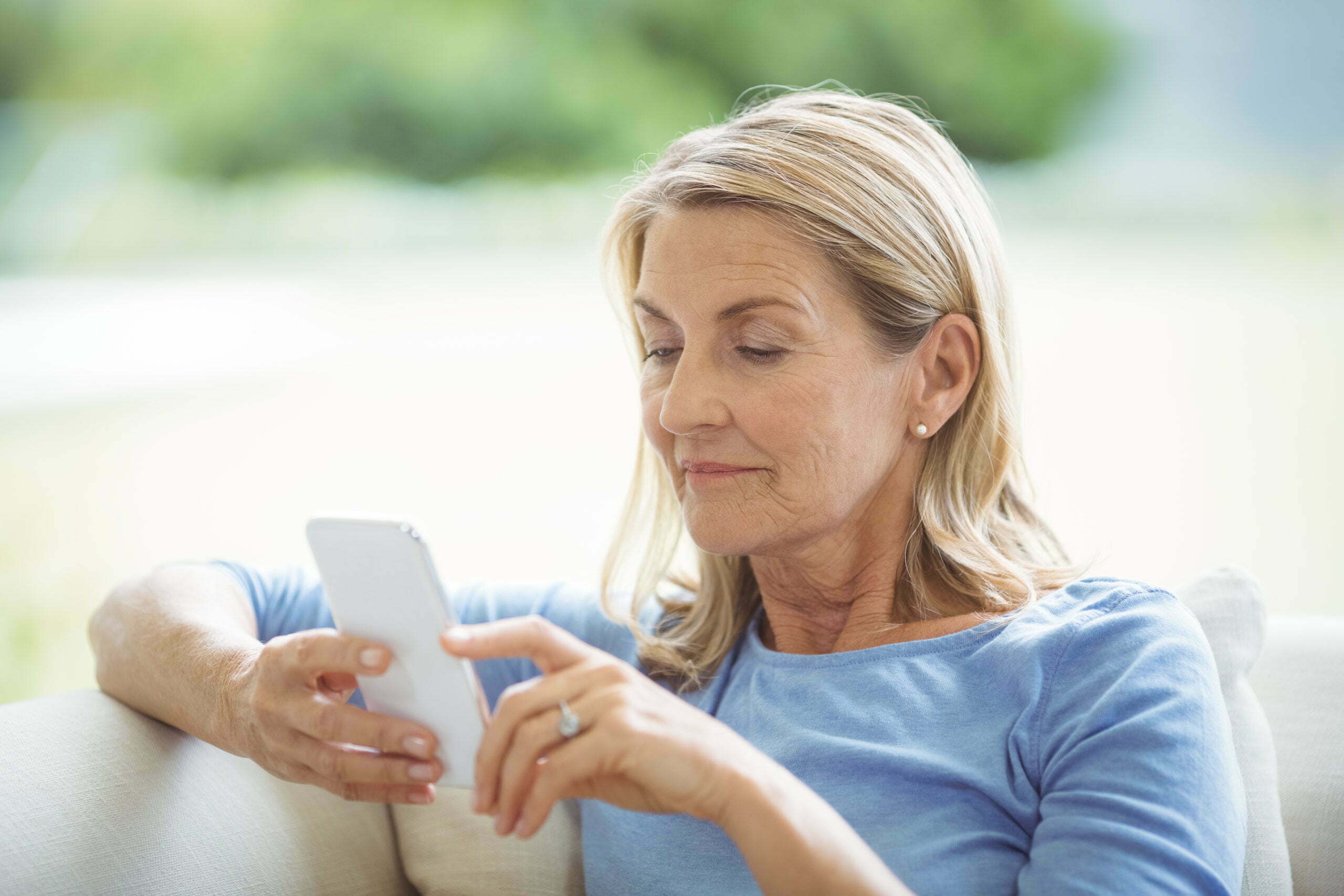 Senior woman using mobile phone in living room